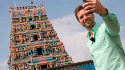 Das Bild zeigt Daniel Aßmann vor dem Sri-Kamadchi-Ampal-Tempel in Hamm.