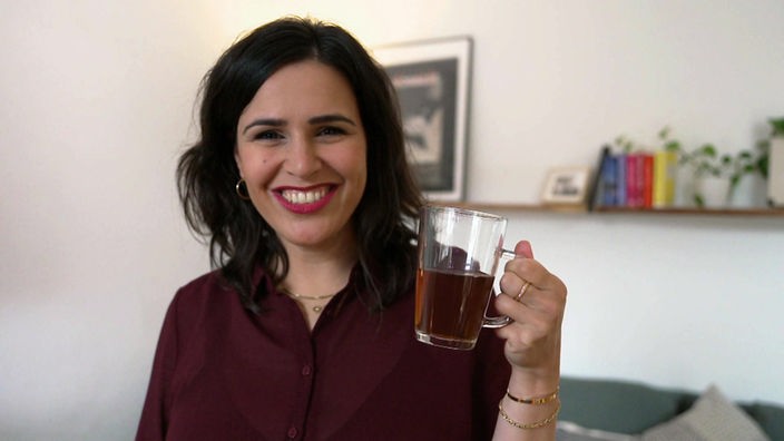 Reporterin Donya Farahani hält einen Tee in der Hand.