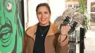 Reporterin Donya Farahani hält ein paar Sneaker in den Händen.