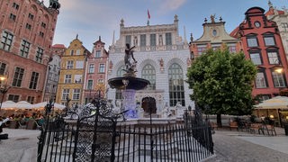 Das Foto zeigt den Neptunbrunnen und den Artushof am langen Markt in Danzig.