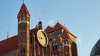 Das Foto zeigt die Marienkirche in Dazig mit ihrem großen Uhrenblatt im Sonnenschein.