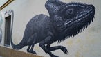Das Bild zeigt ein Graffiti eines schwarzen Chamäleons.