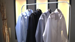 Das Bild zeigt Hemden an einer Kleiderstange aufgehängt.