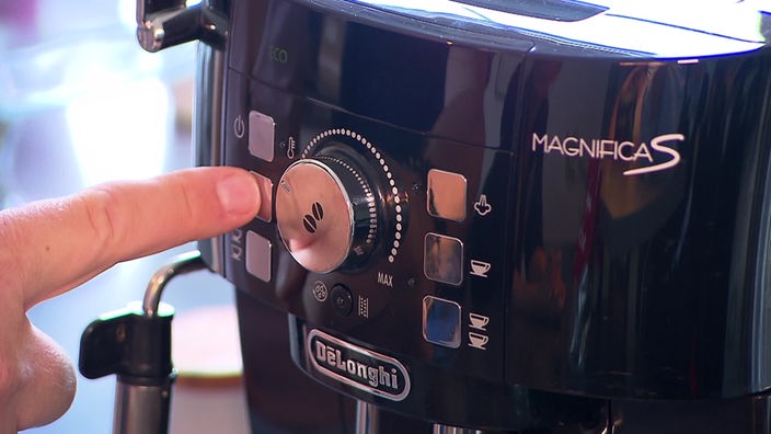 Das Bild zeigt, wie ein Kaffeevollautomat von DeLonghi bedient wird.