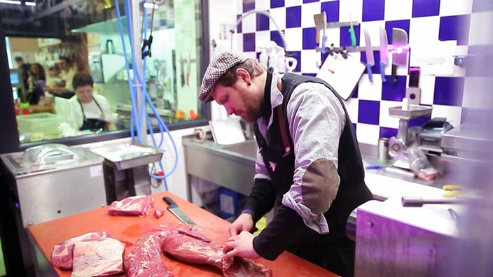 Das Bild zeigt einen Fleischermeister bei der Arbeit.