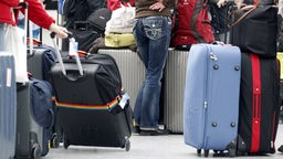 Das Bild zeigt Menschen mit Gepäck am Flughafen.