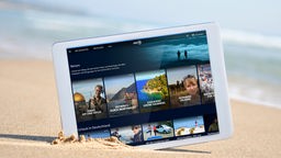 Tablet mit der Startseite der Mediathek-Themenwelt Reisen steckt im Sand