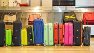 Das Bild zeigt viele Koffer nebeneinander am Kofferband am Flughafen.