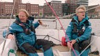 Das Bild zeigt Björn Freitag und den Segler Hanno bei einer Stadtrundfahrt vom Segelboot aus auf den Kieler Förden.