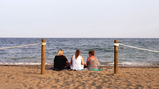 Das Bild zeig drei Frauen im Urlaub am Meer.