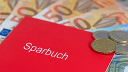 Ein rotes Sparbuch liegt auf 50-Euro-Scheinen