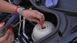 Eine Handwerkerin prüft den Ölstand eines Autos