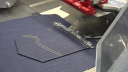 Eine Tasche wird per Maschine auf eine Jeans genäht