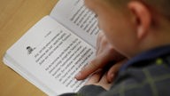 Das Bild zeigt ein Grundschulkind, das in einem Buch liest.
