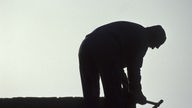 Das Bild zeigt einen Arbeiter im Schatten.