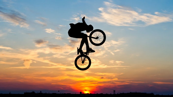 Springender BMX-Fahrer vor Sonnenuntergang