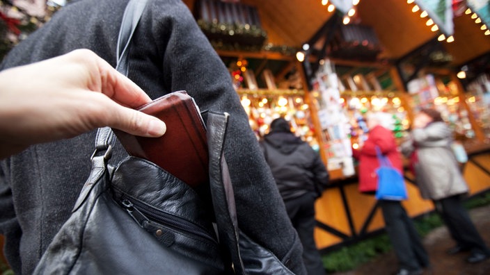 Das Bild zeigt wie einer Weihnachtsmarkt-Besucherin die Geldbörse aus der Handtasche gezogen wird.