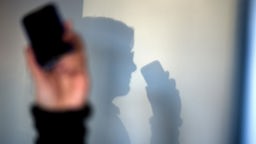 Das Bild zeigt den Schatten einer Person, die telefoniert.