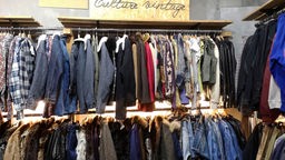 Kleiderstangen mit Jacken in einem Second Hand Laden