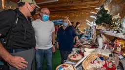 Das Bild zeigt Menschen mit Maske auf dem Weihnachtsmarkt.