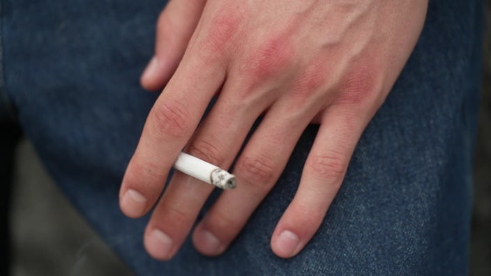 Das Bild zeigt eine Hand, die eine qualmende Zigarette hält.