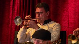 Das Bild zeigt eine männliche Person, die Trompete spielt.