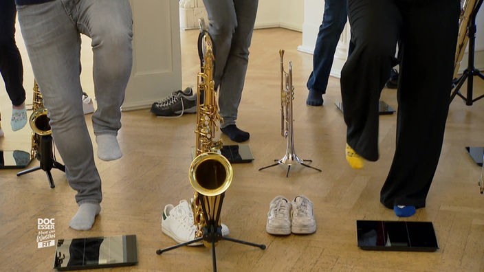 Das Bild zeigt Mitglieder der Big Band auf einem Bein stehend.