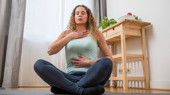 Das Bild zeigt eine Frau, die meditiert.