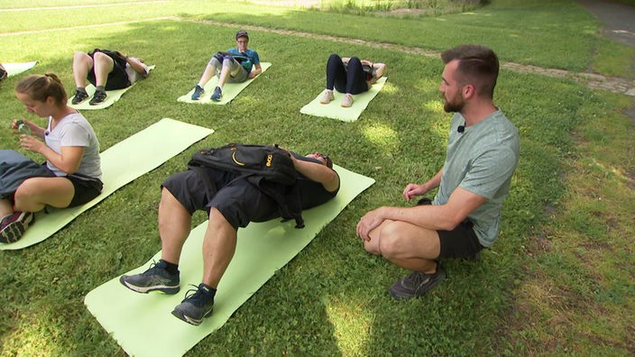 Auf dem Bild sieht man eine Gruppe von Personen mit Doc Esser beim Yoga.