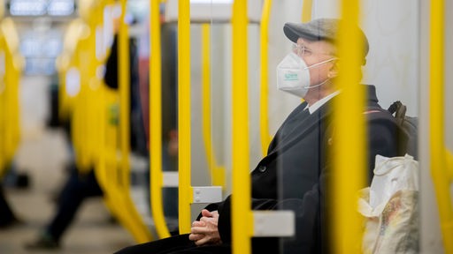 Ein Mann sitzt mit einer FFP2-Maske in einer Straßenbahn.