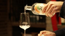 Eine Person gießt alkoholfreien Gin-Ersatz in ein Weinglas.