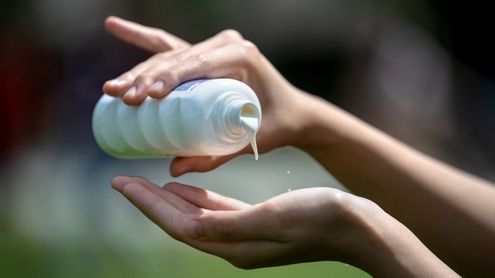 Sonnencreme wird auf die Hand gegeben.