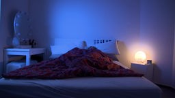Eine Frau schläft in einem Bett mit einer roten Decke