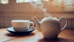 Das Bild zeigt eine dampfende Teekanne und eine Tasse.