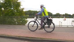 Eine Person fährt mit einem Fahrrad über eine Brücke