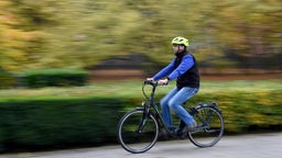 Ein männlicher Fahrradfahrer mit Helm auf einem E-bike