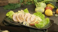 Das Bild zeigt die fertige Hähnchenbrust mit Apfel-Kohlrabi-Salat auf einer Platte.