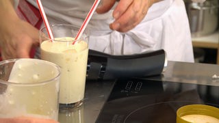 Bananen-Kokos-Drink in einem Glas mit zwei Trinkhalmen
