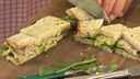 Sandwich mit Avocadocreme wird mit Messer in kleine Happen geschnitten