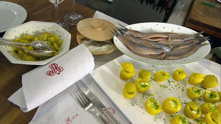 Auf einem Tisch stehen Platten mit jeweils Matjes, Butterfässchen und Kartoffelsalat 