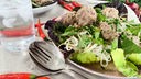 Klopse im Thaicurry mit Salat und Nudeln auf einem Teller angerichtet