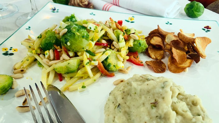 Topinambur auf einer Platte als Salat mit Rosenkohl, als Püree und als Chips angerichtet