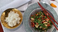 Asia-Hähnchen in einer Schale mit Essstäbchen angerichtet, daneben eine Schale mit Reis