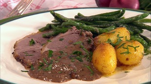 Heidschnuckenbraten mit Wacholdercremesoße, Kartoffeln und grünen Bohnen auf einem Teller angerichtet