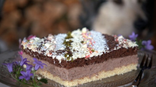 Ein Stück Picklerkuchen mit bunter Verzierung und lila Blümchen