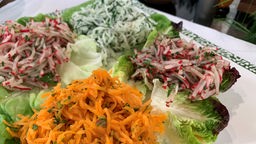 Geraspelte Rettich- und Radieschenportionen mit Salatblättern auf einer Platte angerichtet