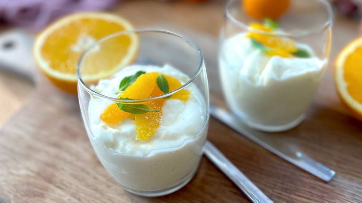 Orangencreme angerichtet in einem Glas mit firschen Orangen getoppt.