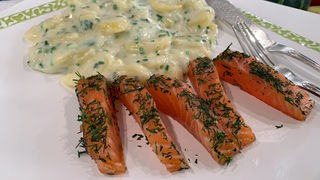 Skandinavische Küche: Lachsstreifen mit Bechamelkartoffeln auf einem Teller angerichtet