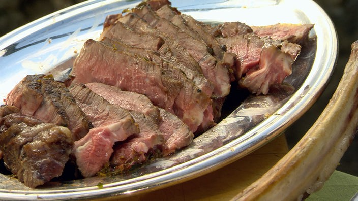 Gegrilltes Fleisch in Scheiben geschnitten und auf einem Teller angerichtet
