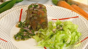 Eine Portion Tafelspitzsülze gestürzt auf einem Teller, dazu grüner Salat